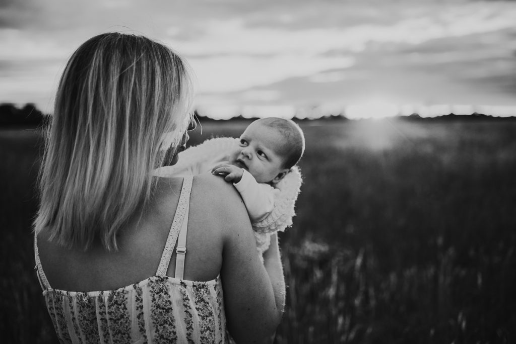 mother and newborn baby in a field during sunset
