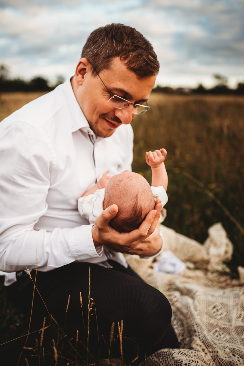 man holding his newborn baby during sunset