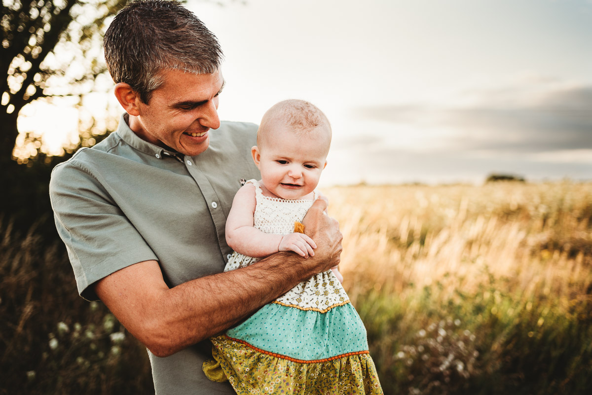 father and his baby girl laughing In a wild meadow