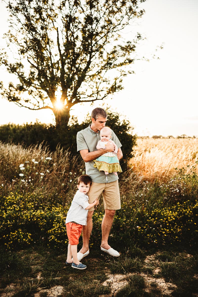 a father and his two children in a wild meadow field