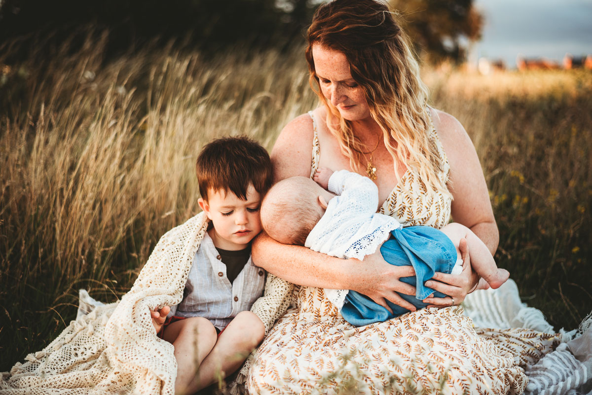 mother breastfeeding her child in the long grass