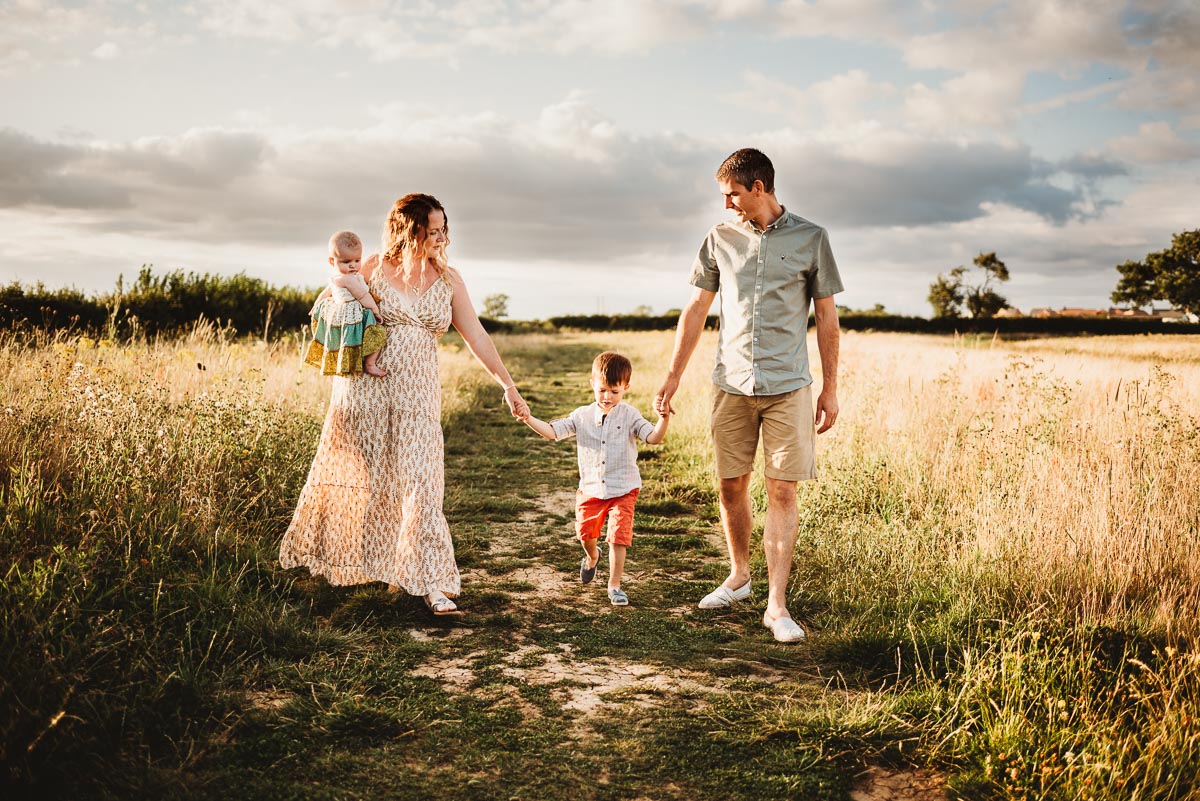 family of 4 walking hand in hand in a wild meadows field