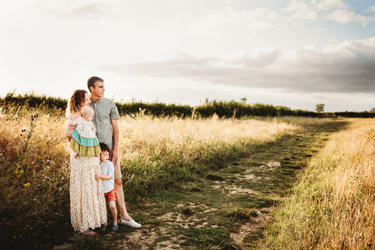family of four standing in a wild meadow field