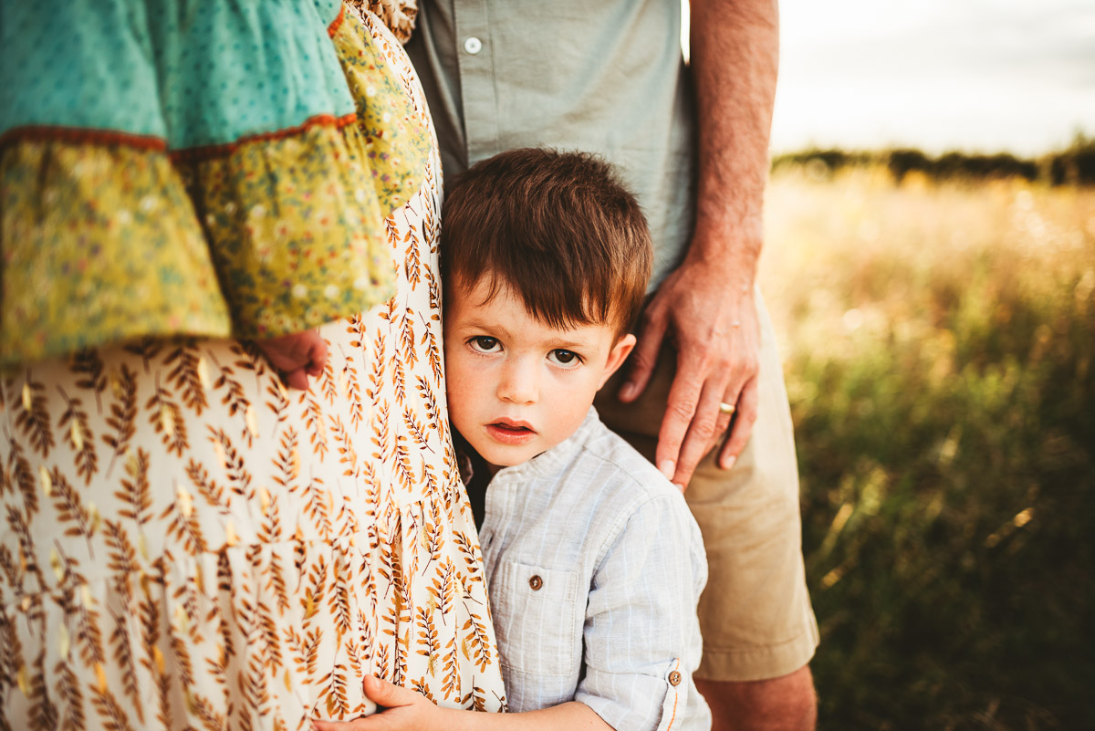 little boy holding onto his mothers leg