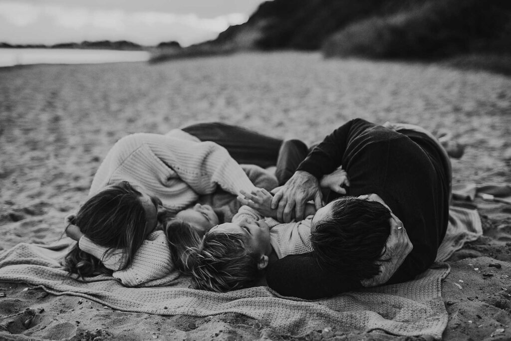family lying on the sand at highcliffe beach