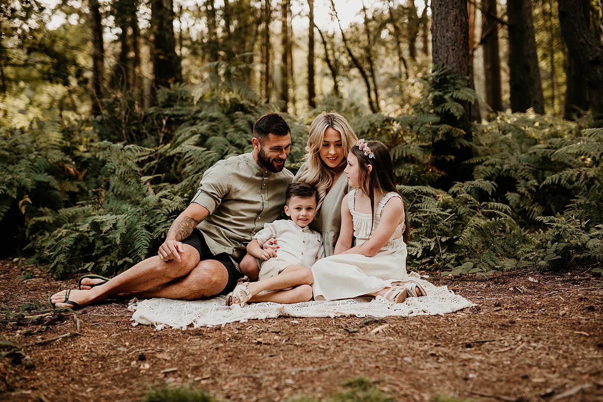 family of four sitting on a blanket in the woods