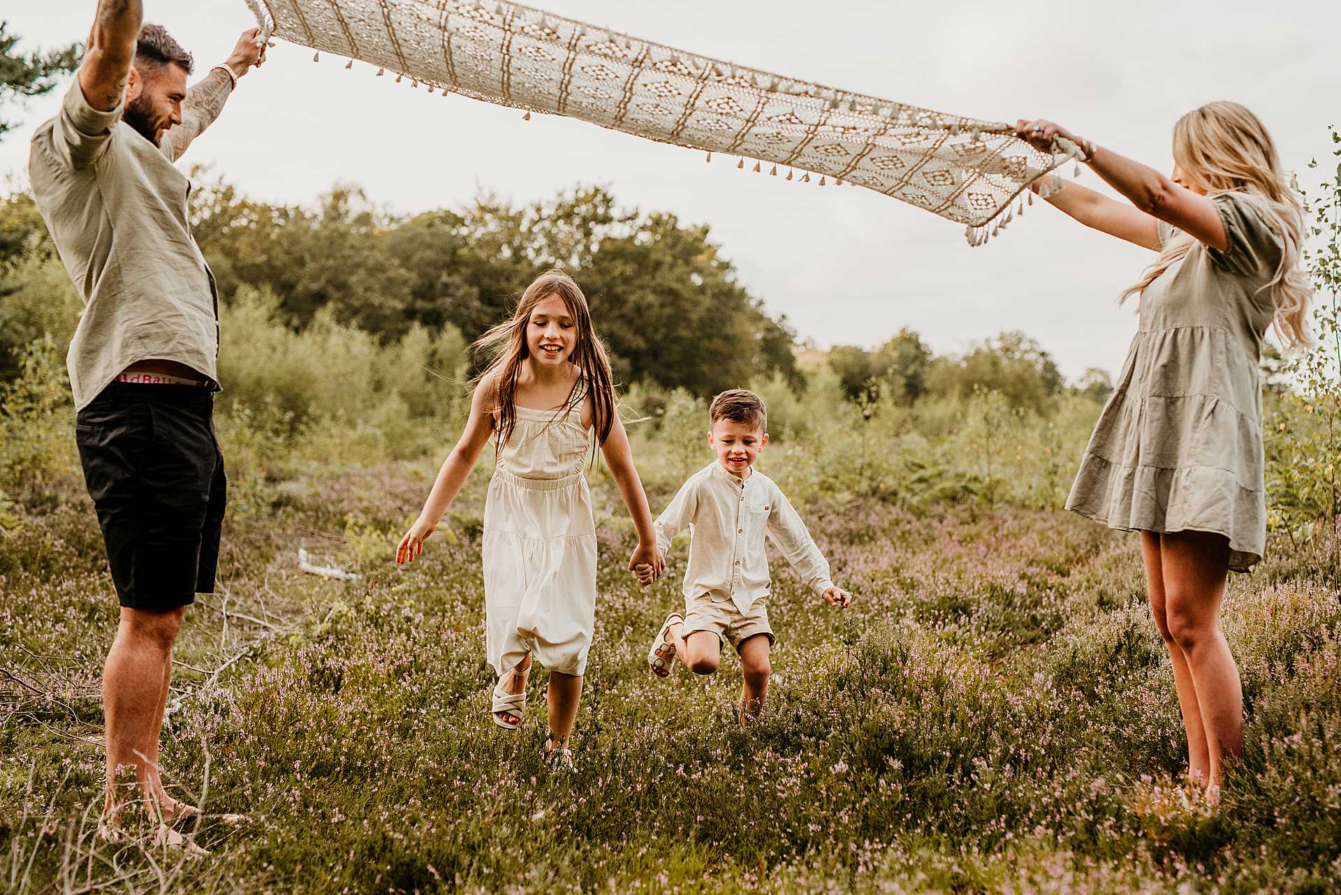 boy and girl running under a blanket that mum and dad are holding up