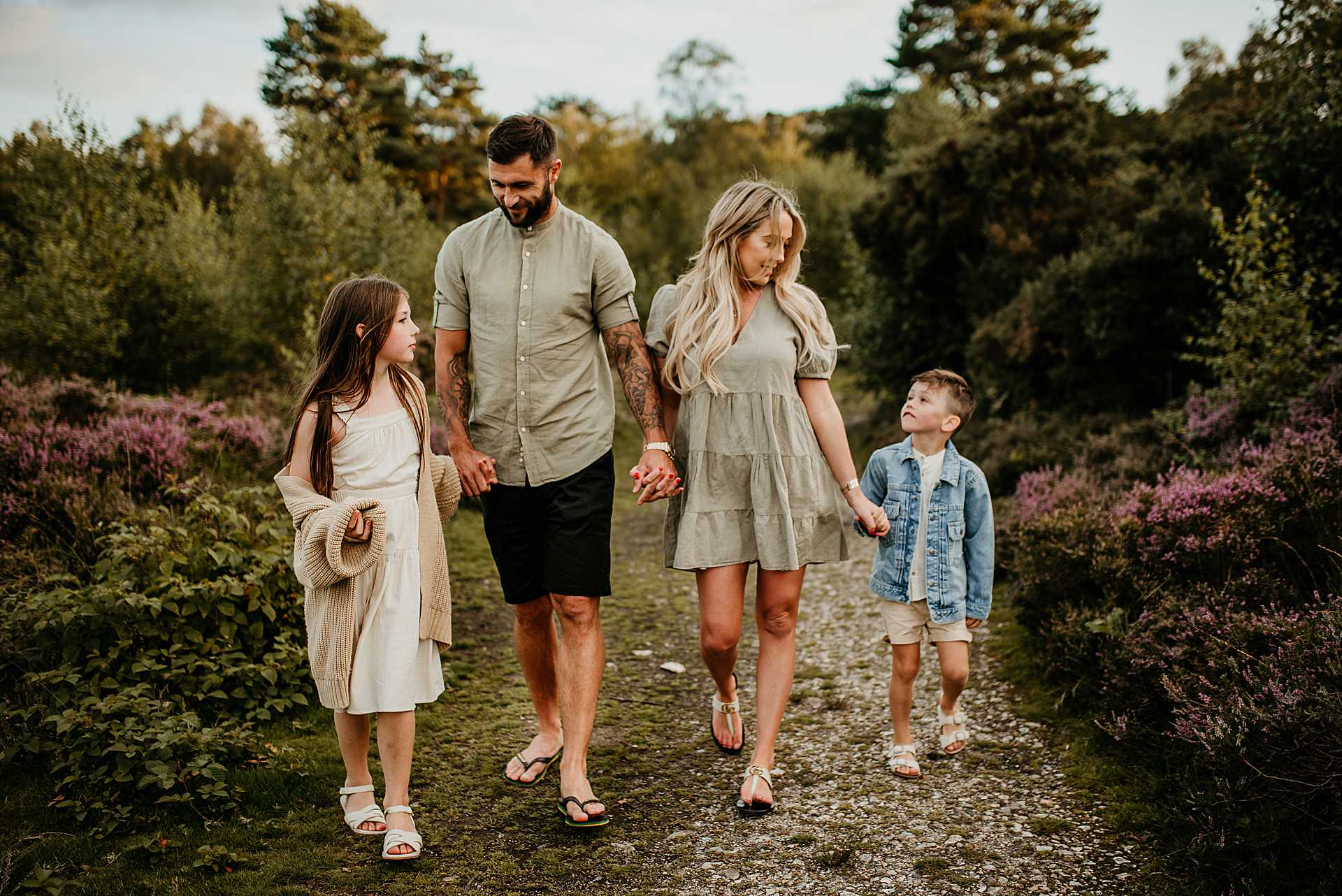 mum and dad with two children walking hand in hand in the woods