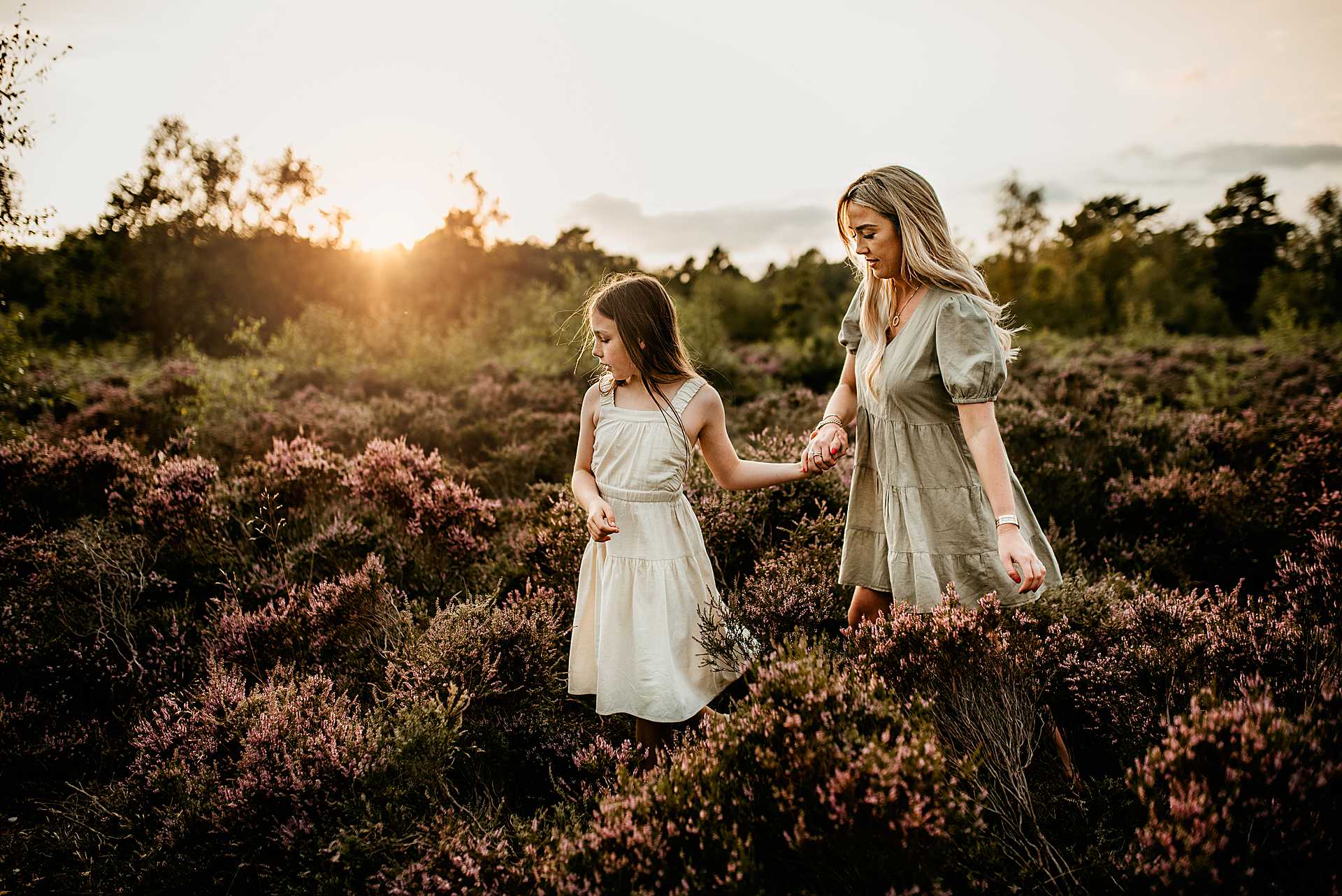 mother and daughter walking hand in hand amongst the purple heather at Snelsmore Common