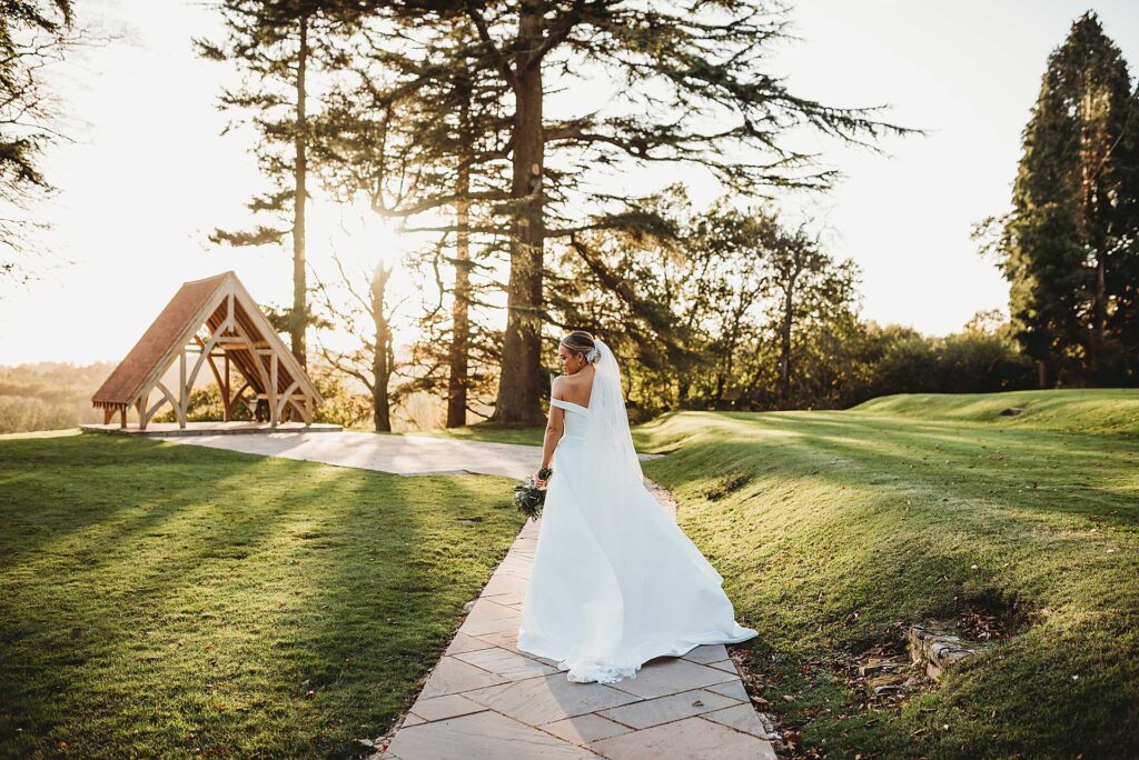 bride walking down a path towards the sunset whilst looking over her shoulder
