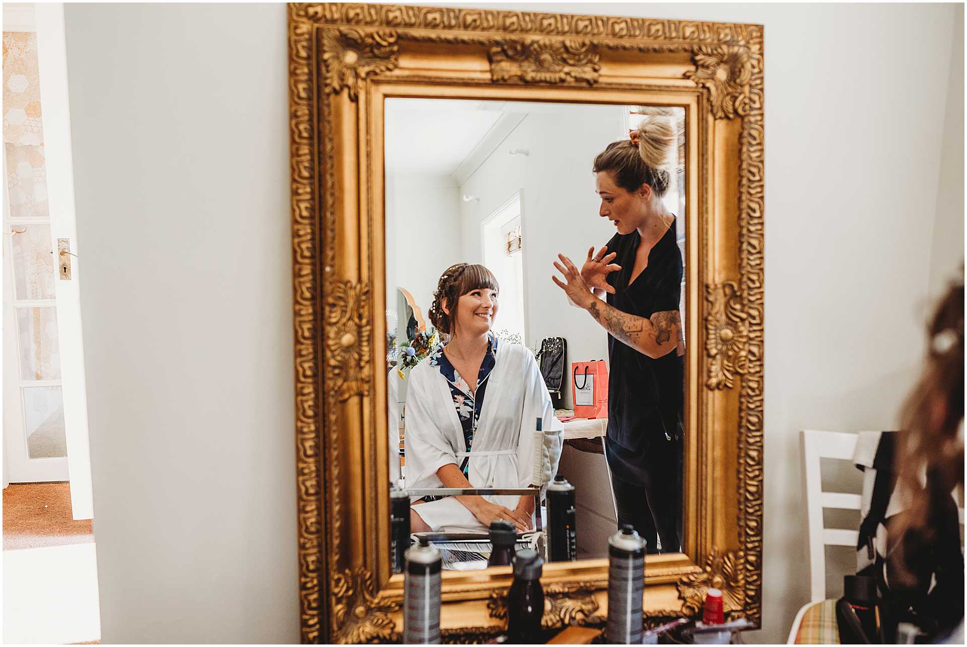 Brides reflection in a mirror as she talks to her hair stylist at a hale park wedding