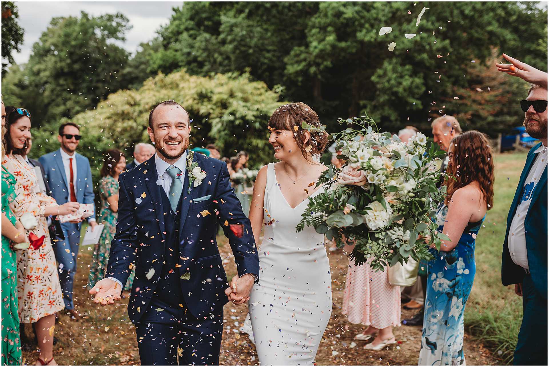 bride and groom walking as guests throw confetti