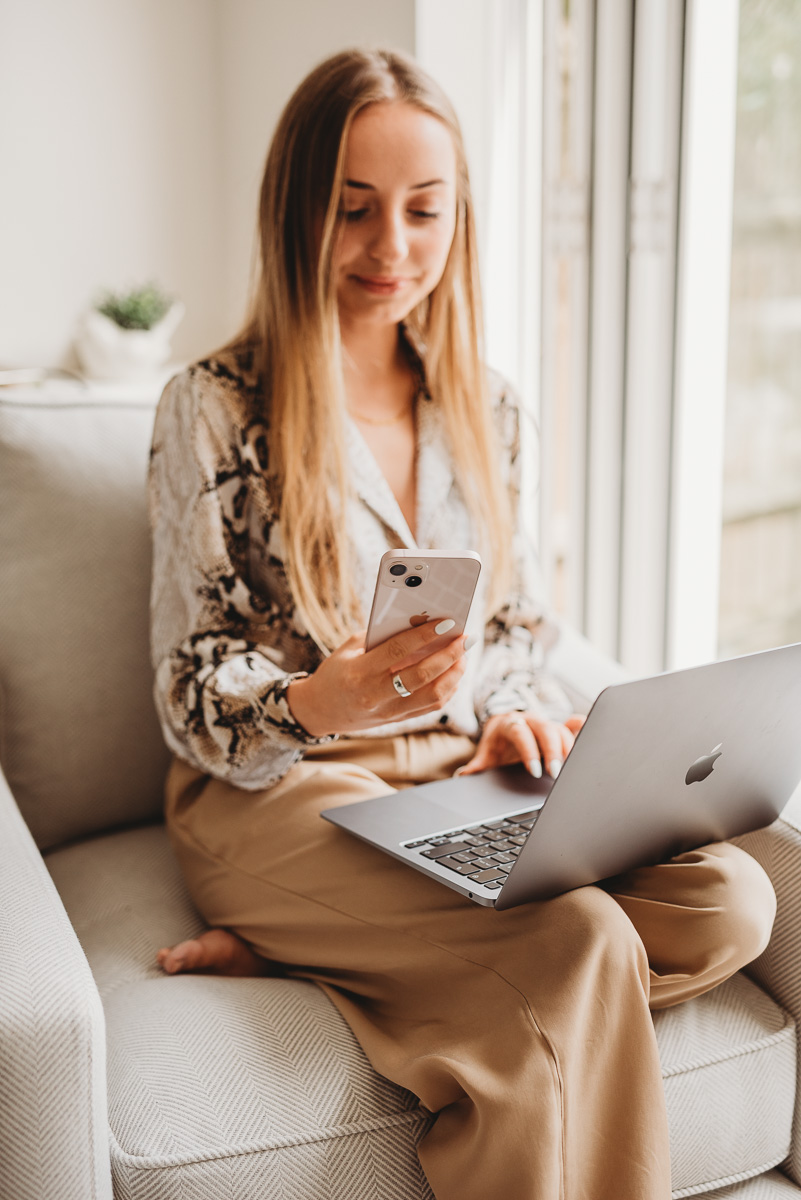 girl working on her laptop and looking at her iPhone