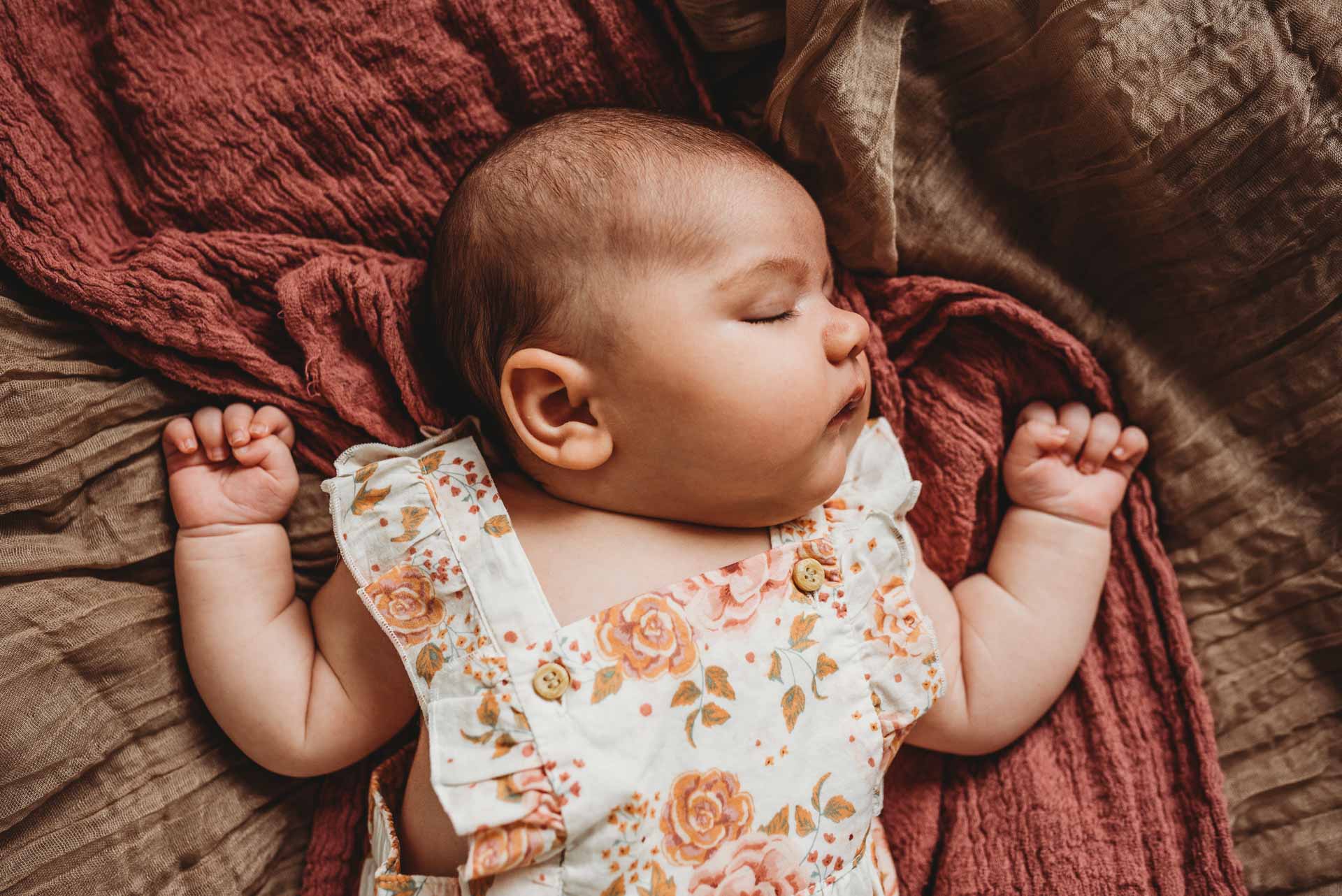 baby sleeping on her back with her arms up