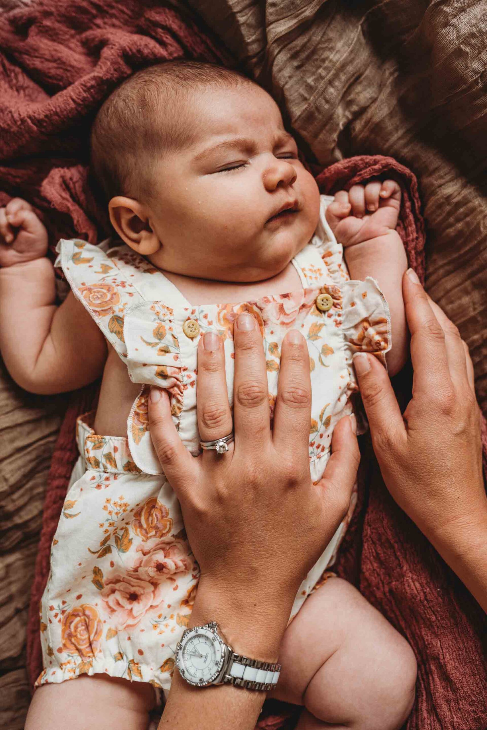 mothers hands on baby as she sleeps