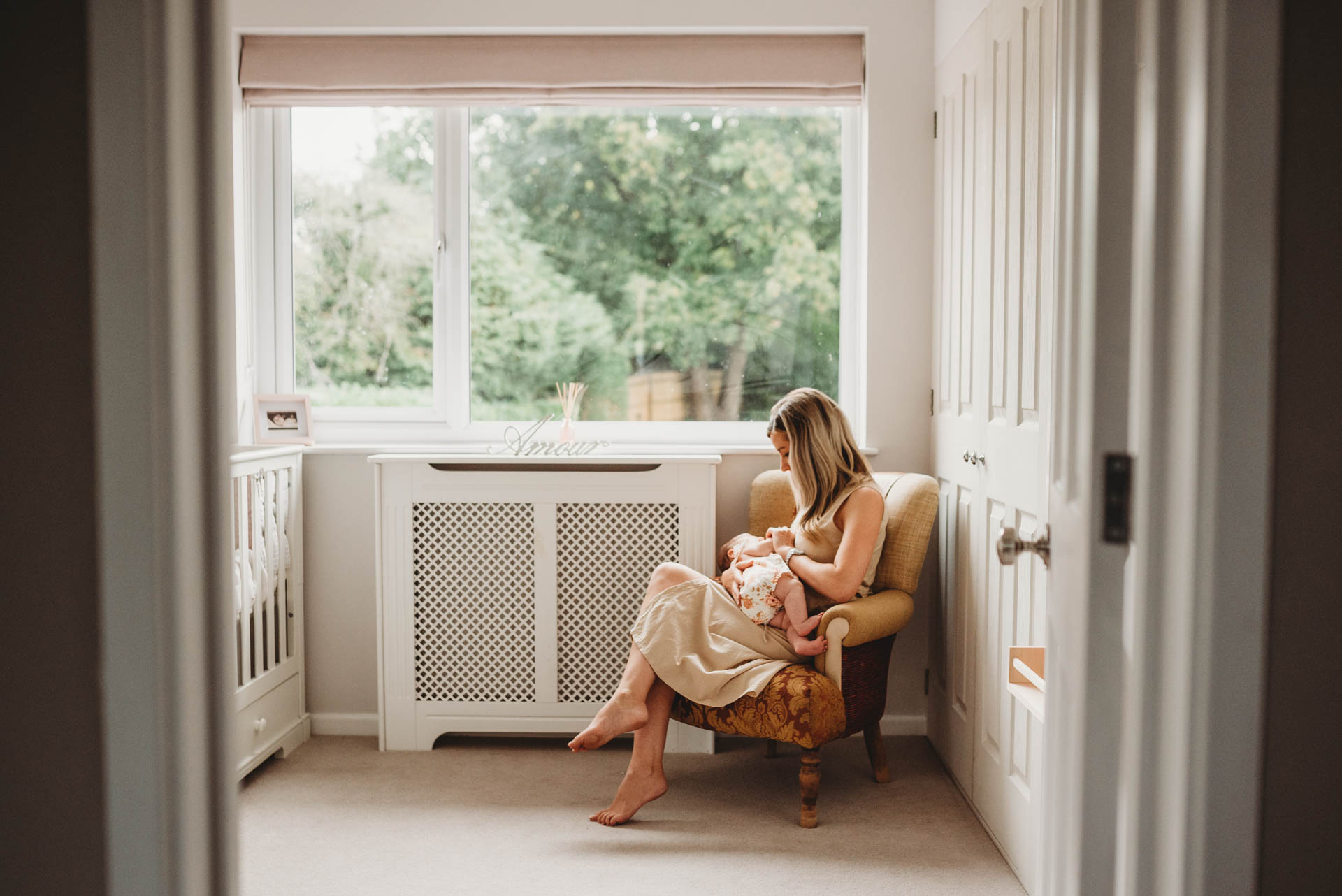 mother sat in a chair breastfeeding her baby girl