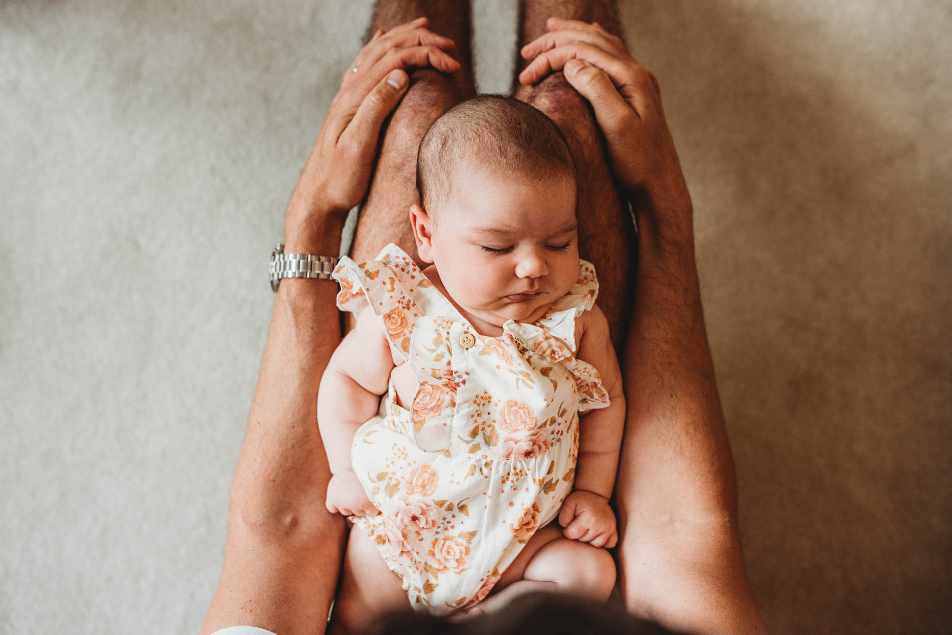 baby sleeping on her fathers legs