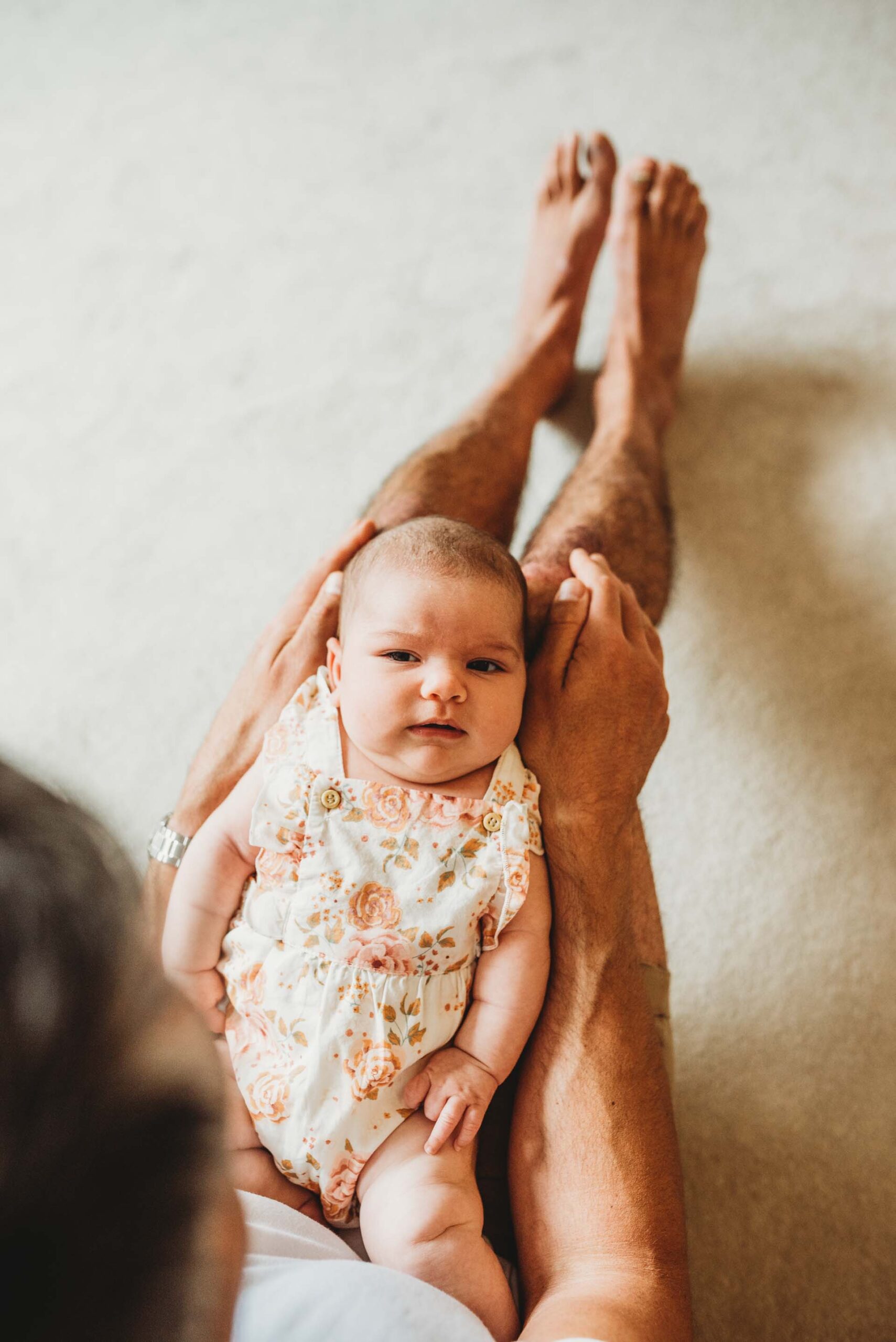 newborn baby lying on dads legs