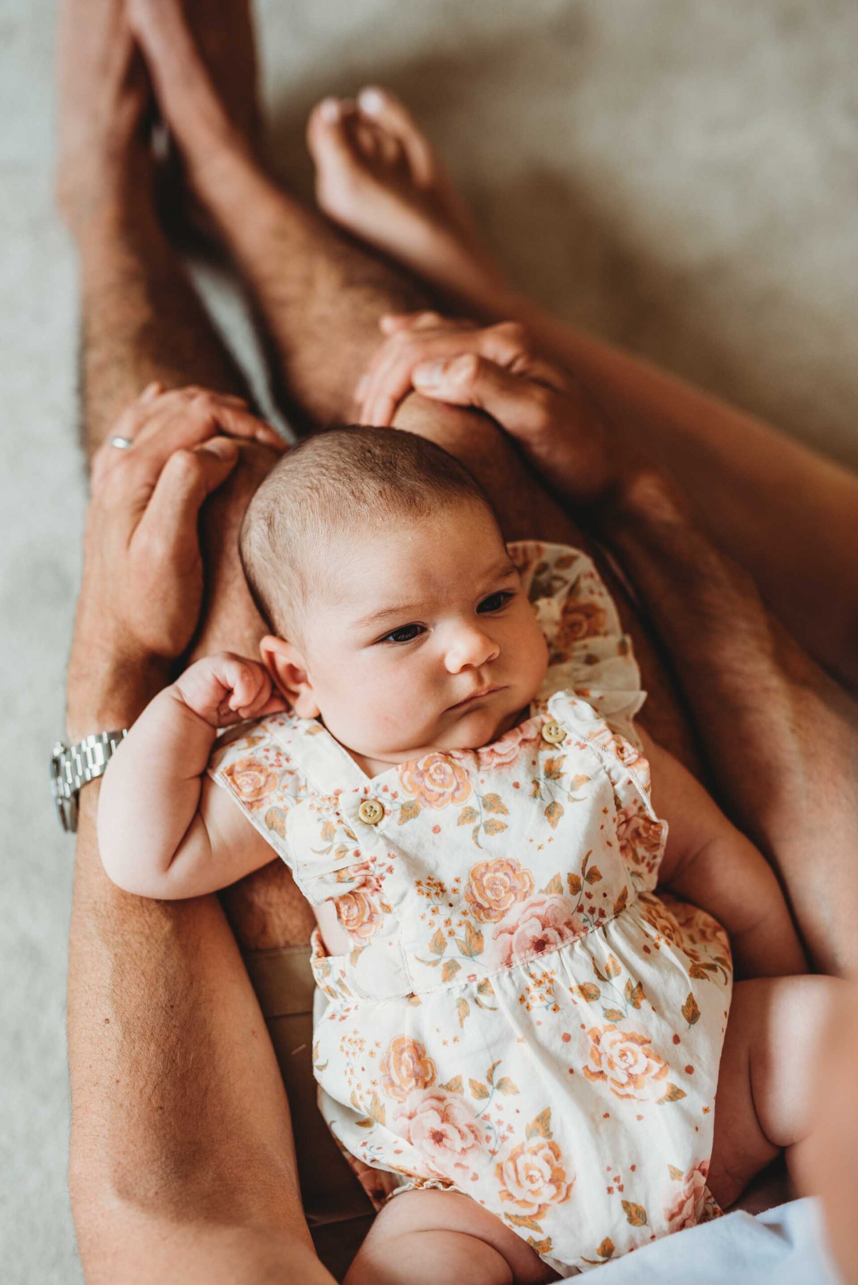 baby girl lying on her dads legs