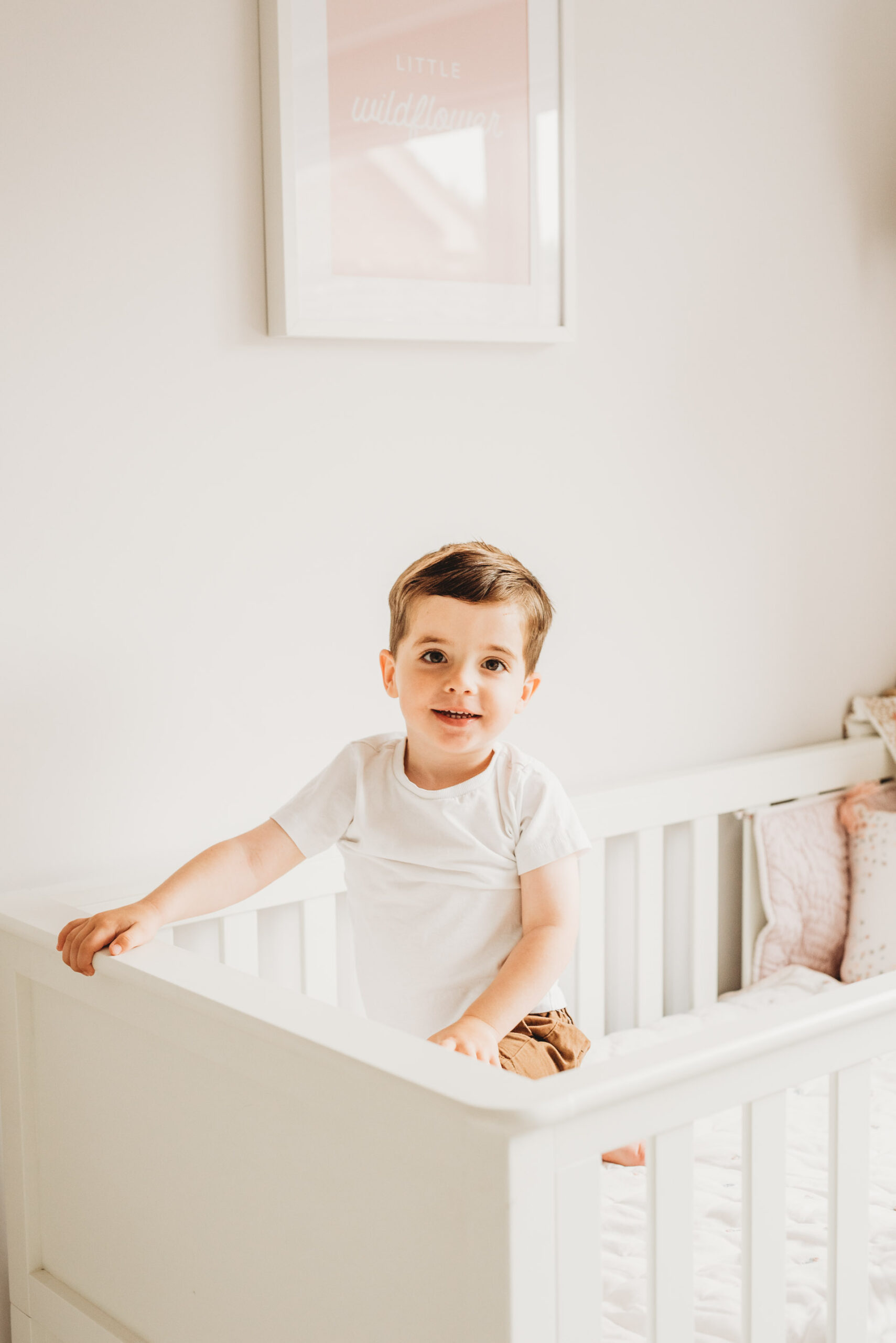 little boy leaning over his baby sisters cot