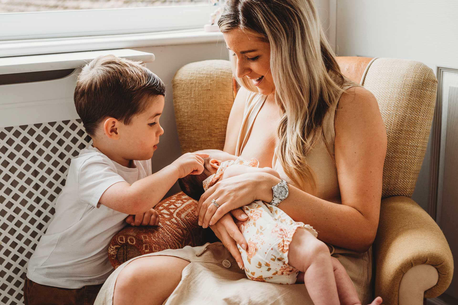 little boy with his mother as she breastfeeds baby