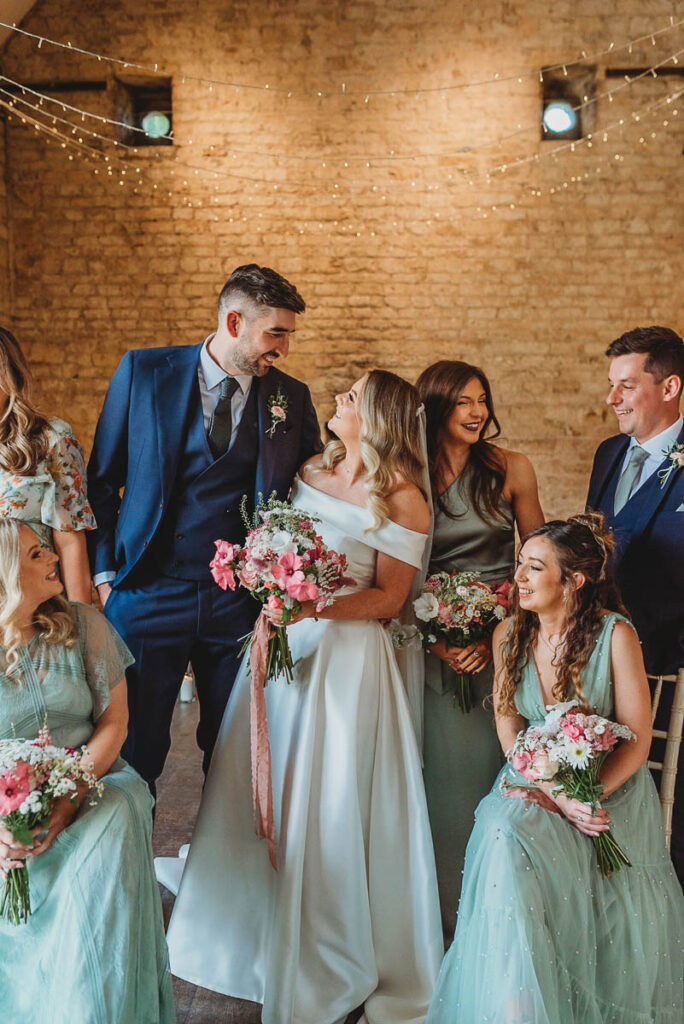 bride and groom walk between their bridesmaids and groomsmen by Wedding Photographer in Wiltshire, the Cotswolds, Gloucestershire and beyond. 
