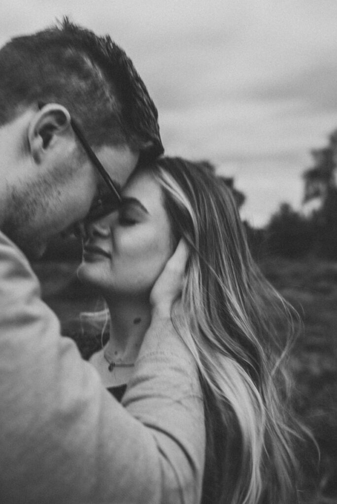 black and white image of a man holding his girlfriends face close to his by authentic Wedding Photographer in Wiltshire