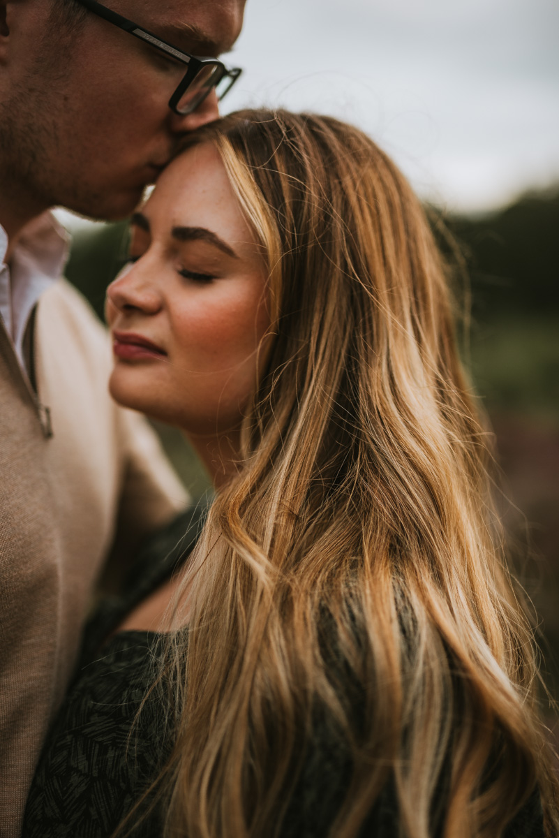 man kissing his girlfriend on the forehead 