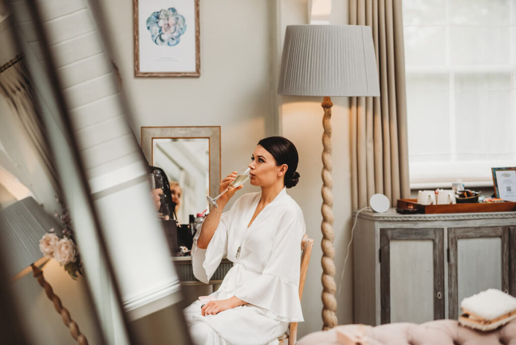 bride sitting drinking champagne whilst getting ready at Syrencot house