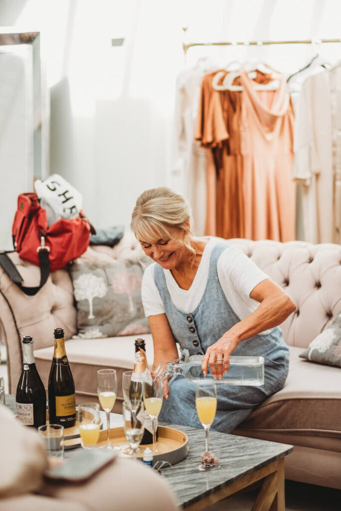 mother of the bride pouring champagne into glasses during bridal prep