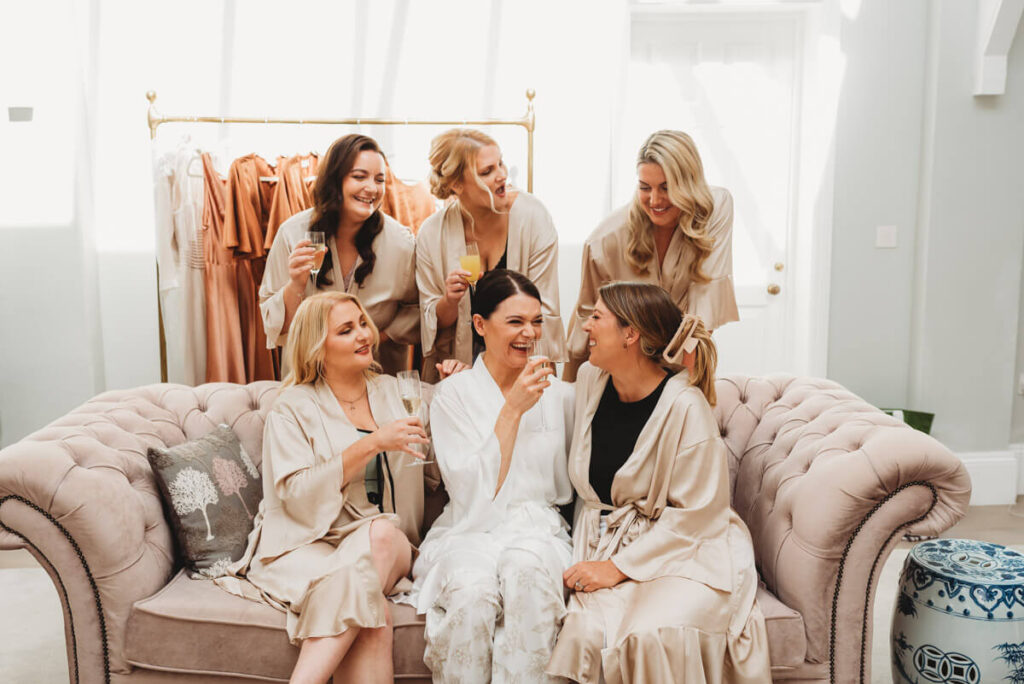 bride and her bridesmaids sitting on sofa at Syrencot laughing and drinking