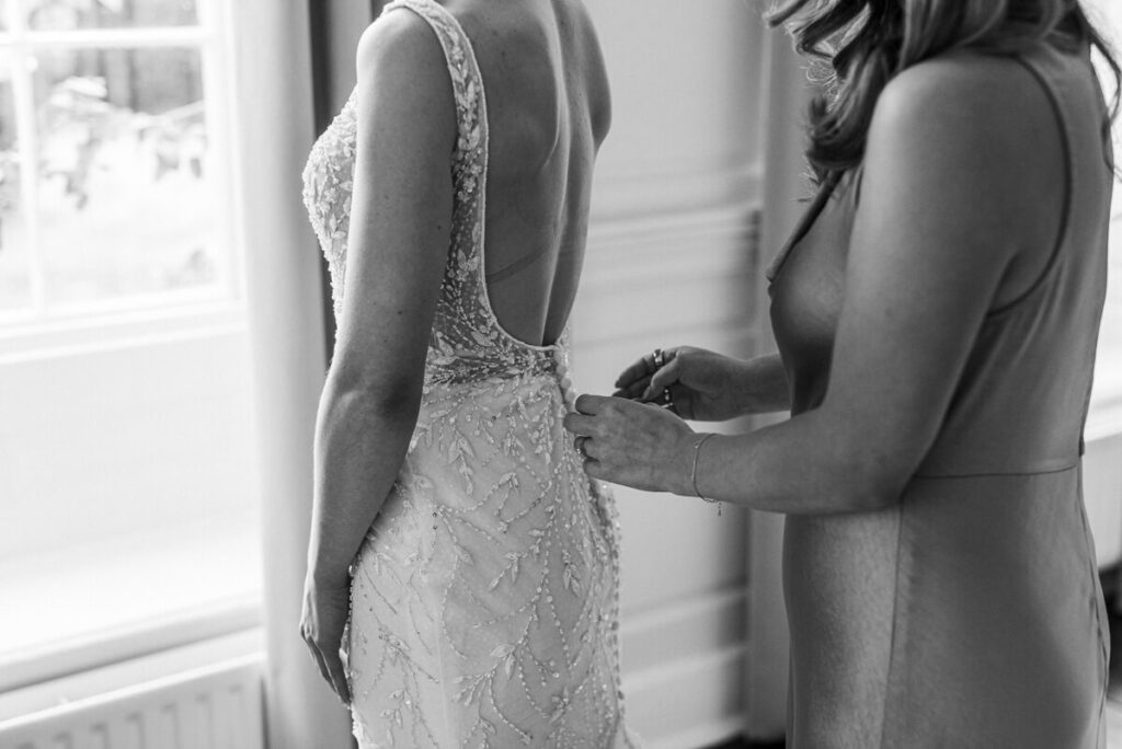 black and white image of bridesmaid doing the brides dress up