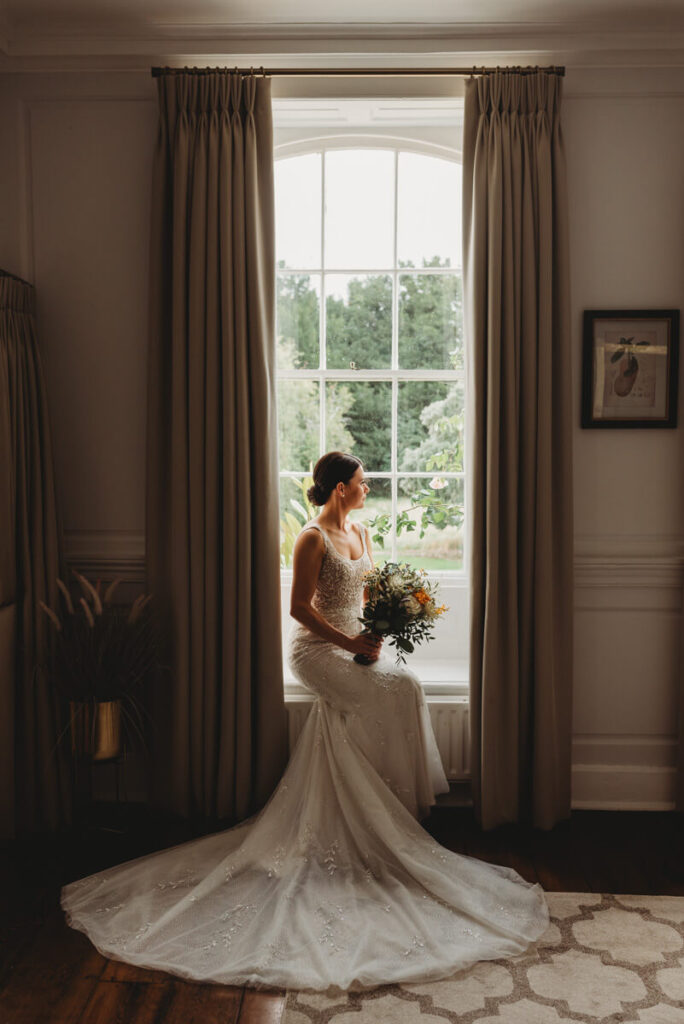 bride sitting in the window holding her bouquet in the bridal suite