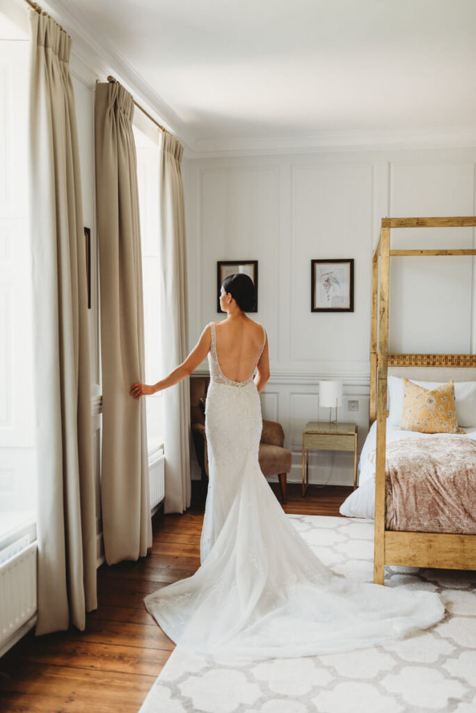 bride looking out the window in her dress before the ceremony starts at Syrencot house