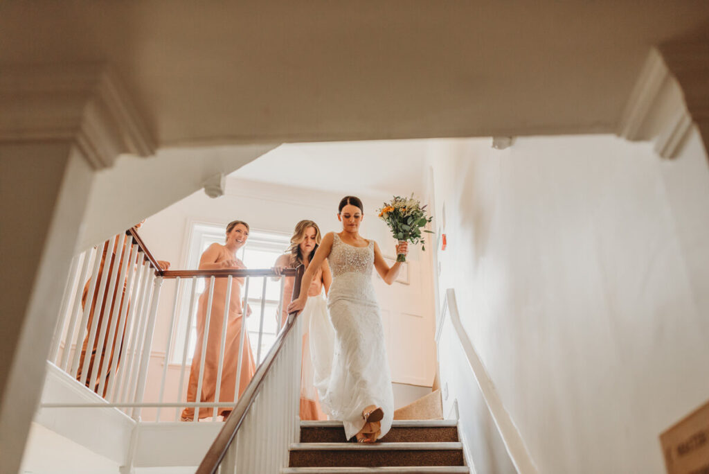 bride and bridesmaid walking down the stairs at Syrencot house