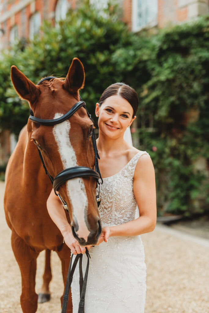 bride with a chestnut horse on her wedding day by Wedding Photographer in Wiltshire, the Cotswolds, Gloucestershire and beyond.