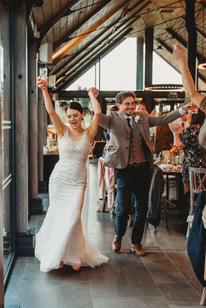 bride and groom wave their arms in the air in celebration by Wedding Photographer in Wiltshire