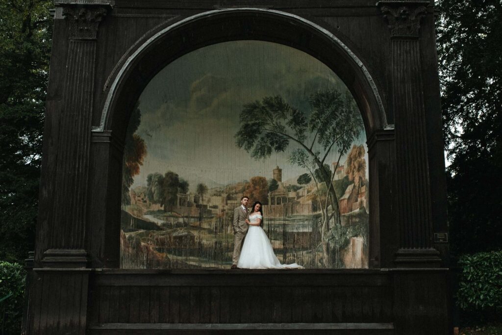bride and groom standing in the singing theatre during the rain at Larmer Tree Gardens