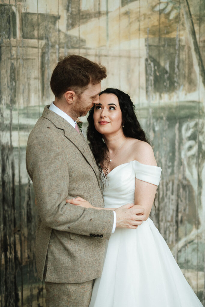 bride and groom standing in the singing theatre during the rain at Larmer Tree Gardens