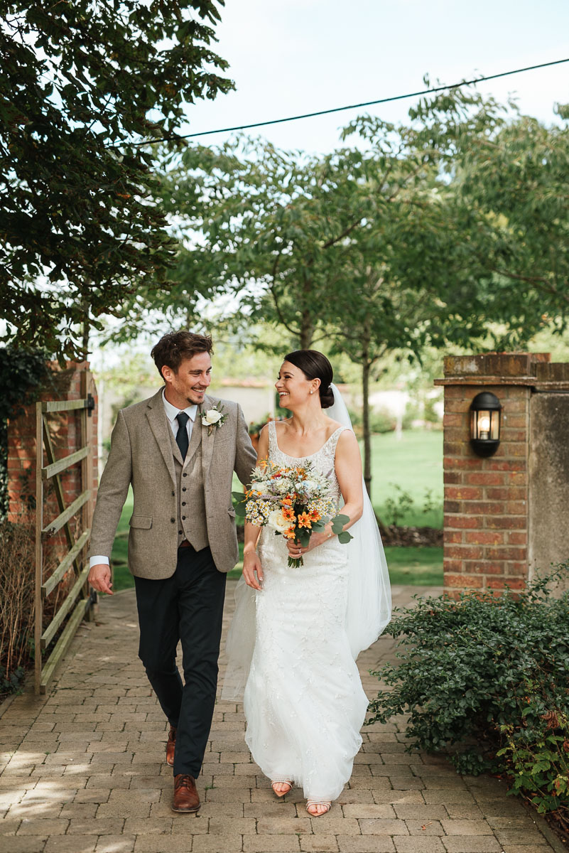 bride and groom looking at each other as they walk through the grounds at syrencot house