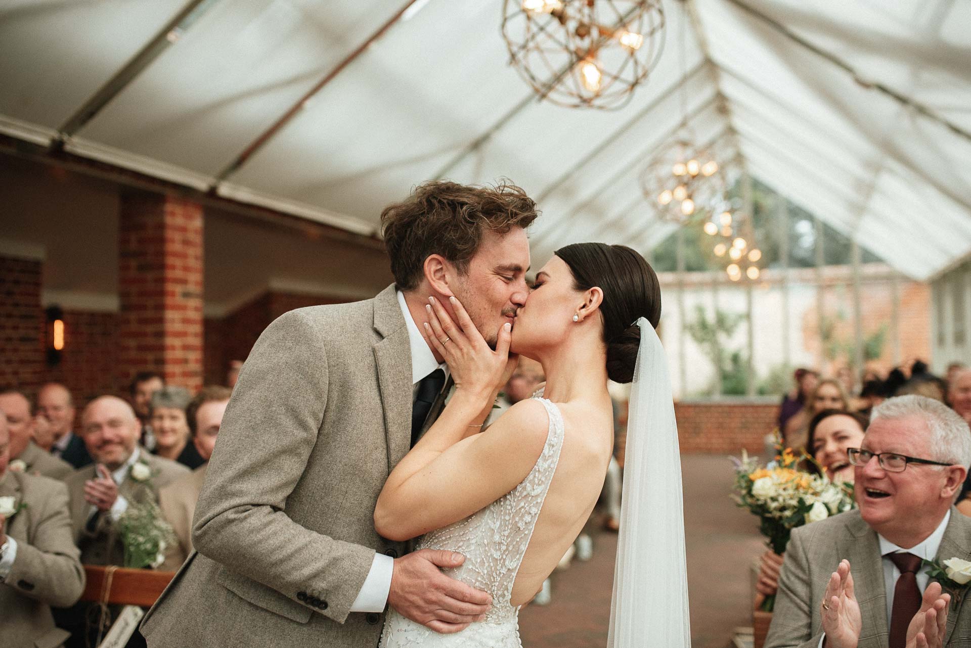 bride and grooms first kiss as they stand at the alter at syrencot house