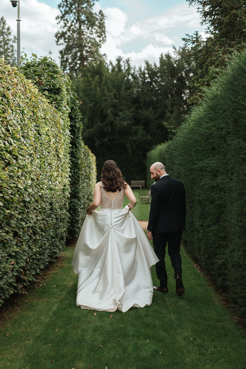 bride lifting her dress as she walks with her husband leading the way at Grittleton house