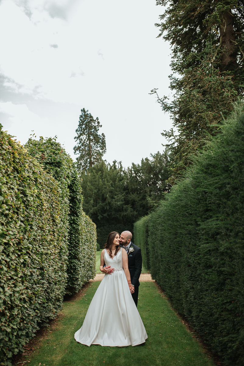 groom kissing his bride on the cheek as she leans into him at grittleton house wedding venue