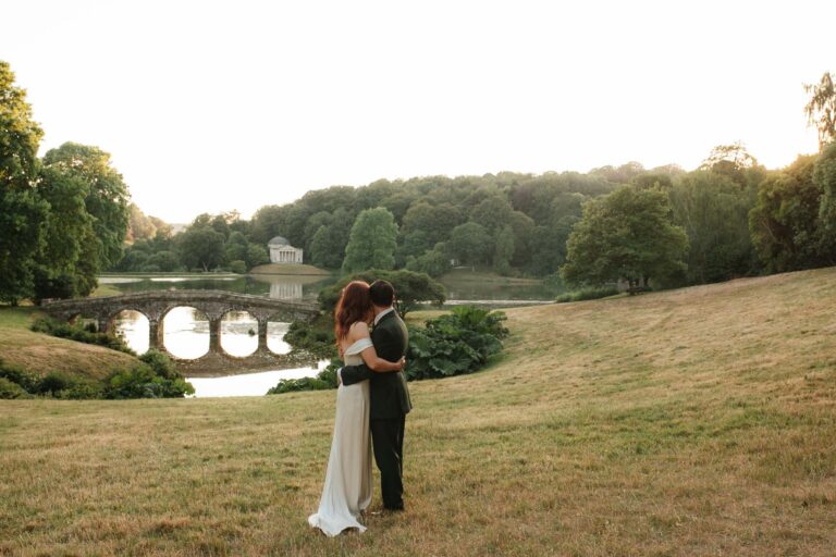 bride and groom embracing near the bridge at stourhead gardens