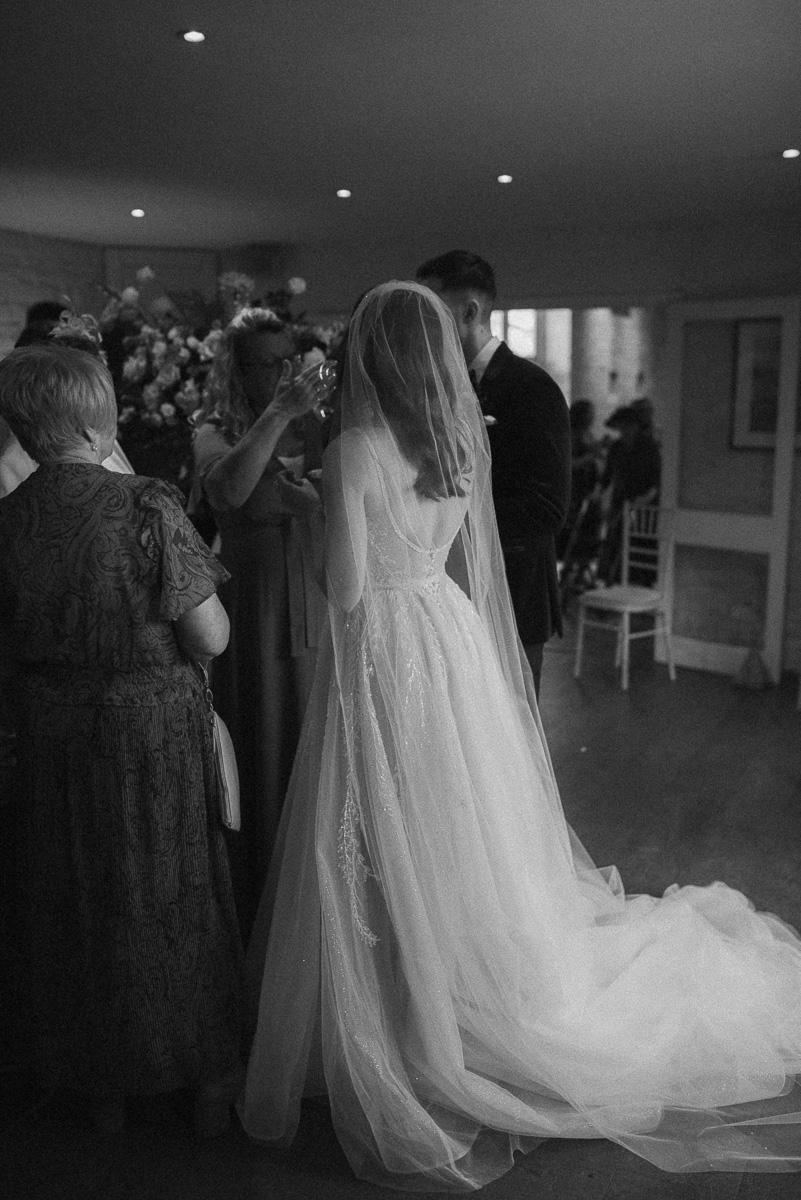 black and white portrait of a bride talking to guests at Lapstone barn wedding venue