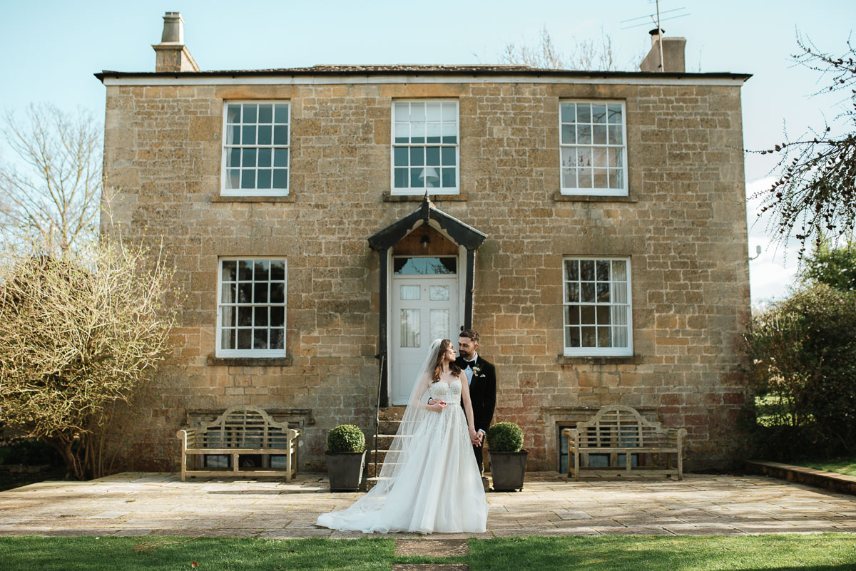 bride and groom standing infant of the Manor House at Lapstone Barn wedding venue