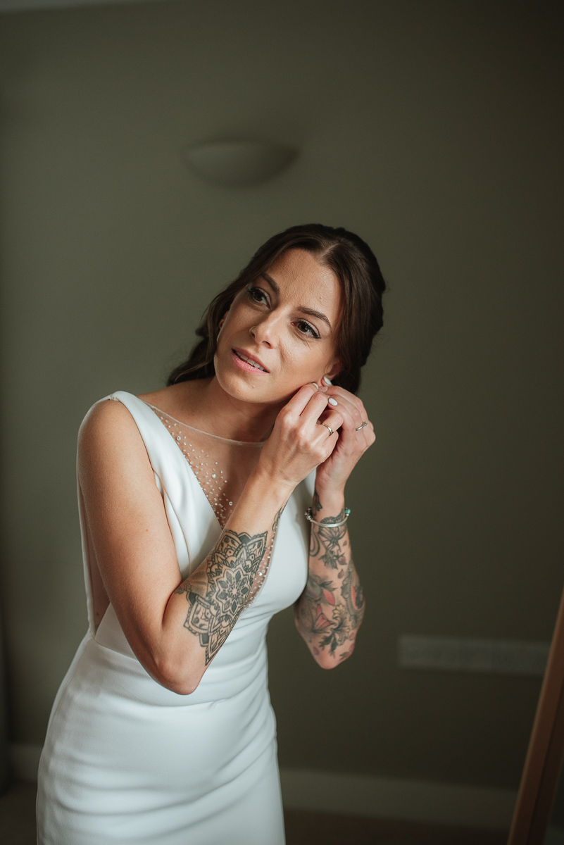 bride putting in her earrings before her boho inspired micro wedding