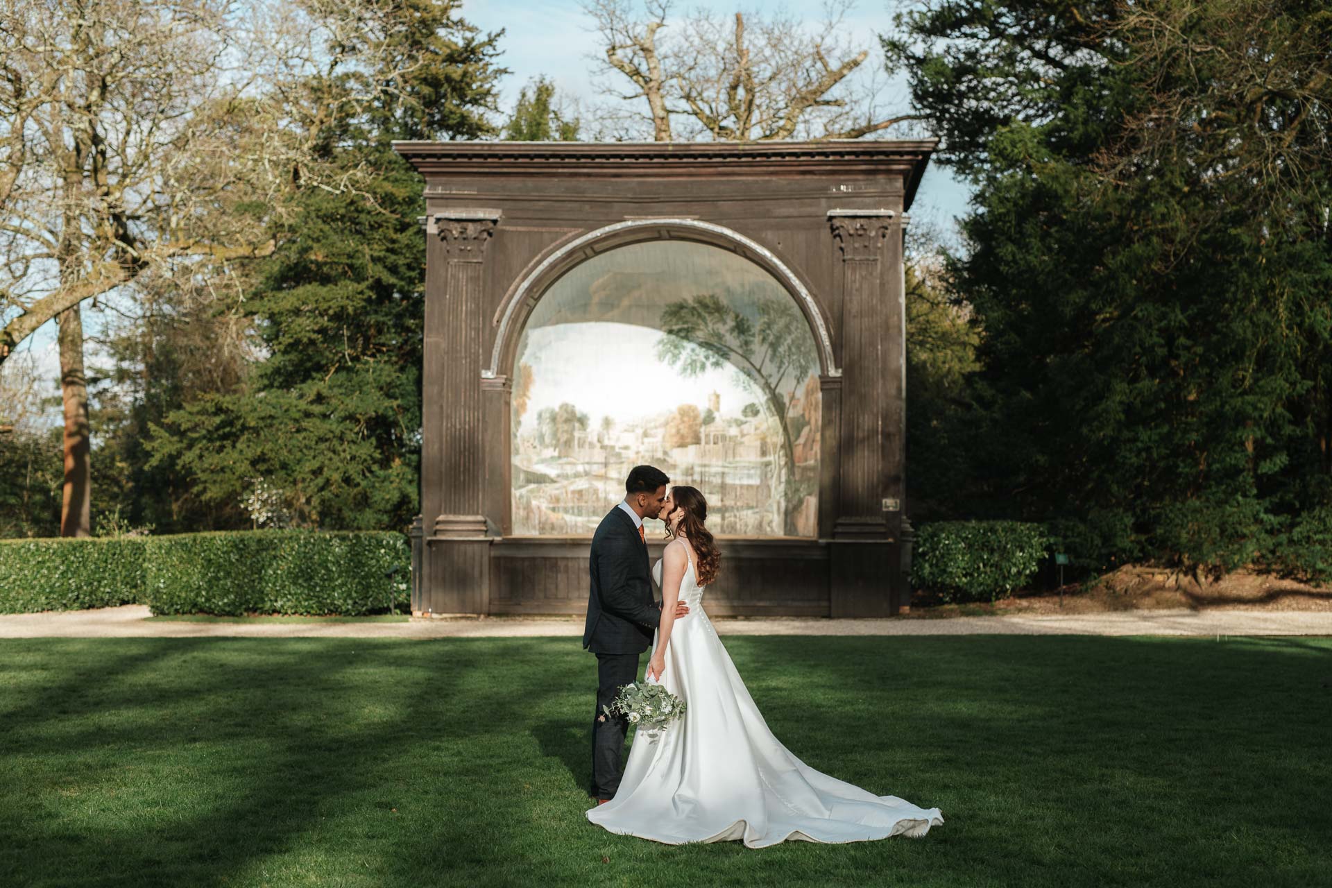 bride and groom kissing outside in the Larmer Tree Gardens with the pavilion in the background
