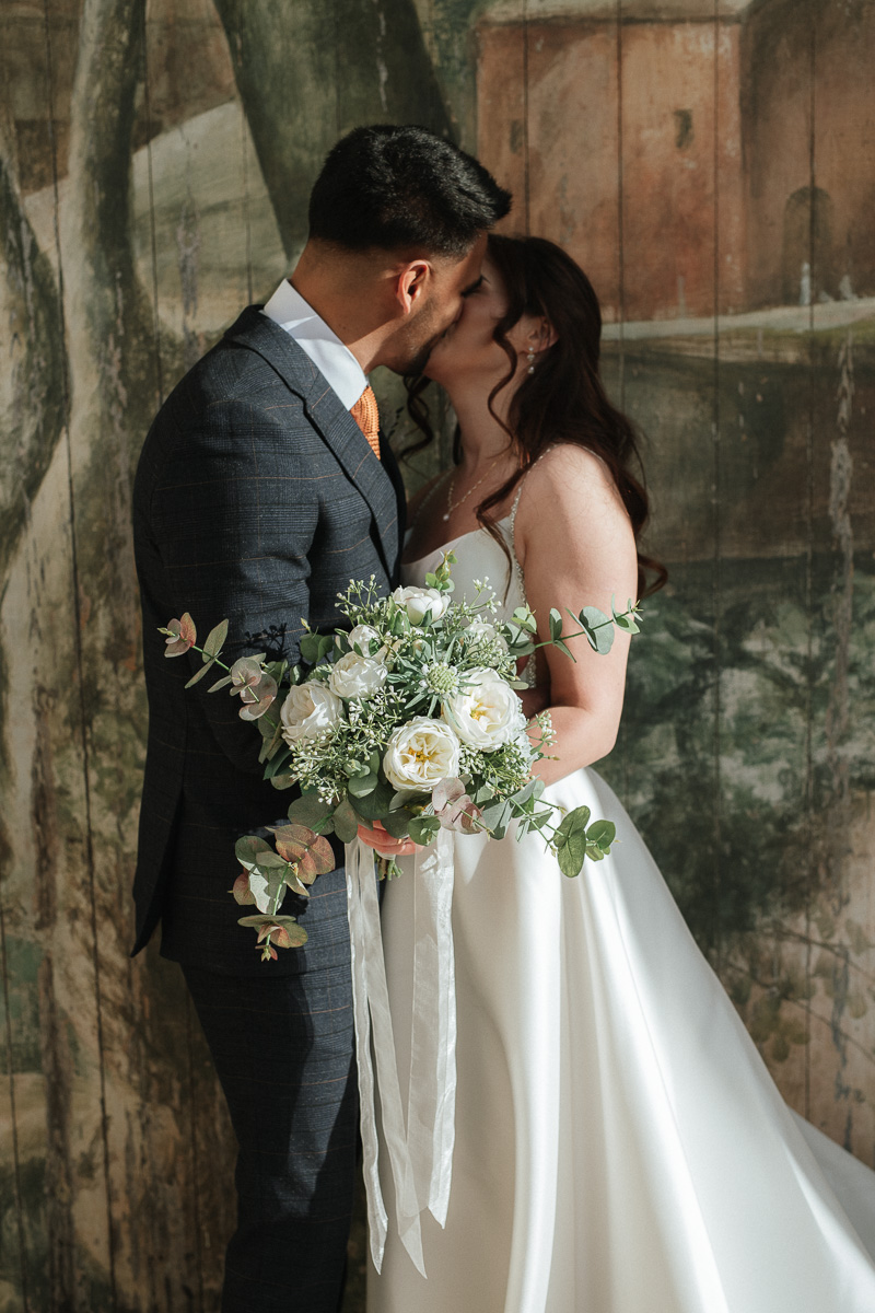 bride and groom share a kiss in the pavilion at The Larmer Tree wedding venue after their micro wedding ceremony