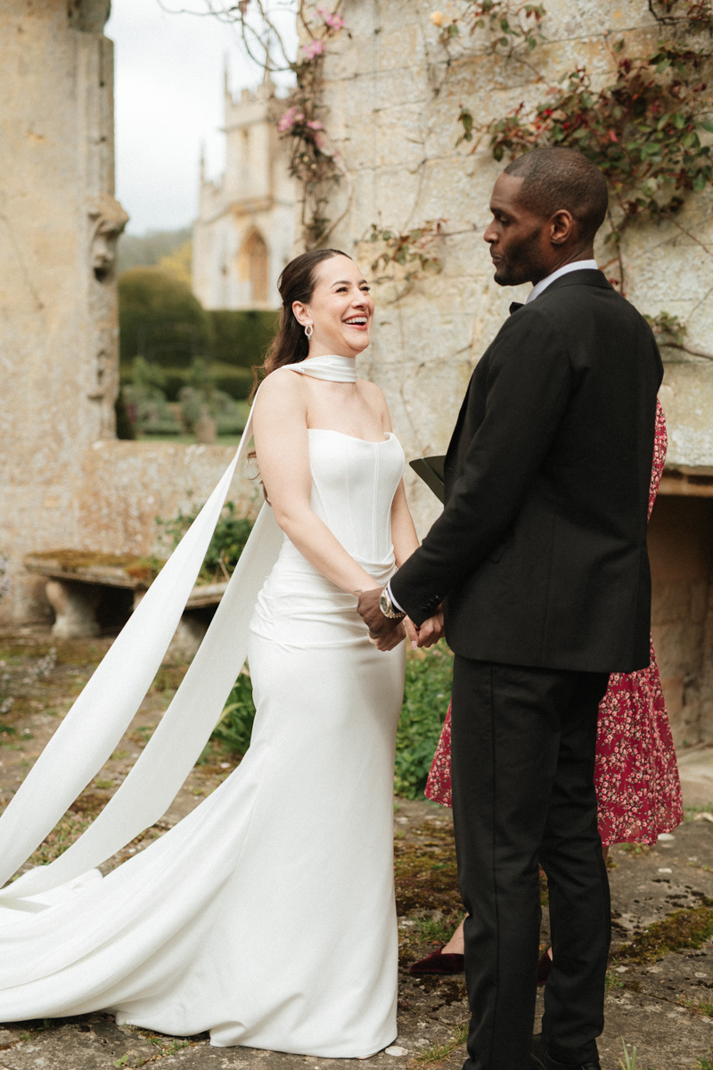 bride and groom standing holding hands saying their vows to another in the ruins of Sudelely Castle